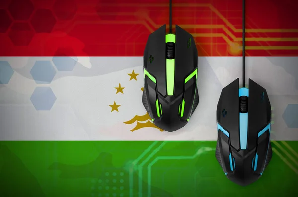 Tajikistan flag  and two modern computer mice with backlight. The concept of online cooperative games. Cyber sport team