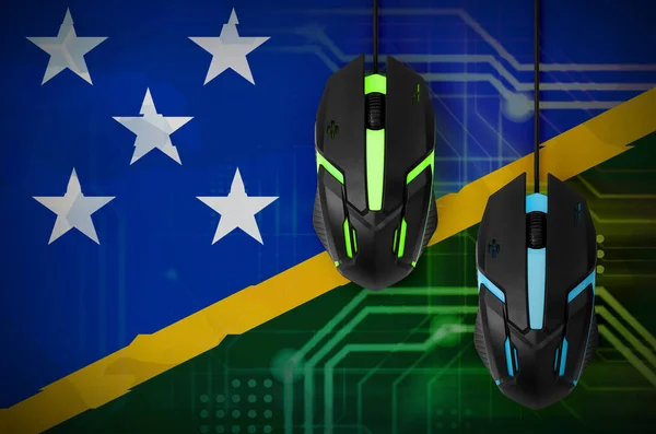 Solomon Islands flag  and two modern computer mice with backlight. The concept of online cooperative games. Cyber sport team