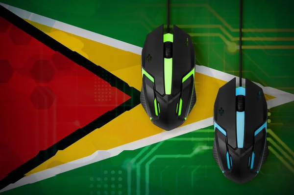 Guyana flag  and two modern computer mice with backlight. The concept of online cooperative games. Cyber sport team