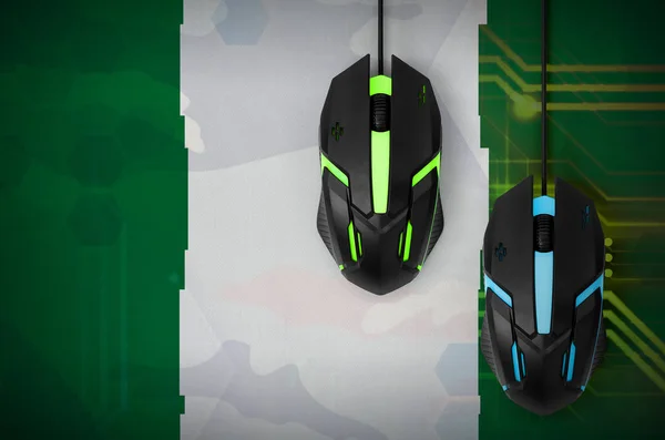 Nigeria flag  and two modern computer mice with backlight. The concept of online cooperative games. Cyber sport team
