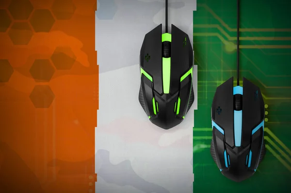 Ivory Coast flag  and two modern computer mice with backlight. The concept of online cooperative games. Cyber sport team