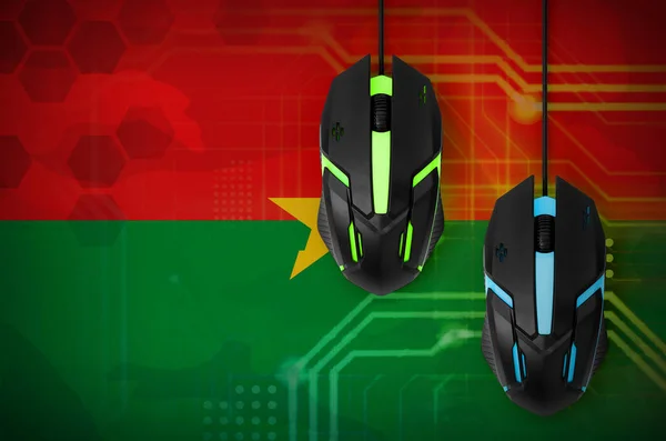 Burkina Faso flag  and two modern computer mice with backlight. The concept of online cooperative games. Cyber sport team