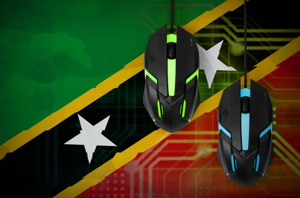 Saint Kitts and Nevis flag  and two modern computer mice with backlight. The concept of online cooperative games. Cyber sport team