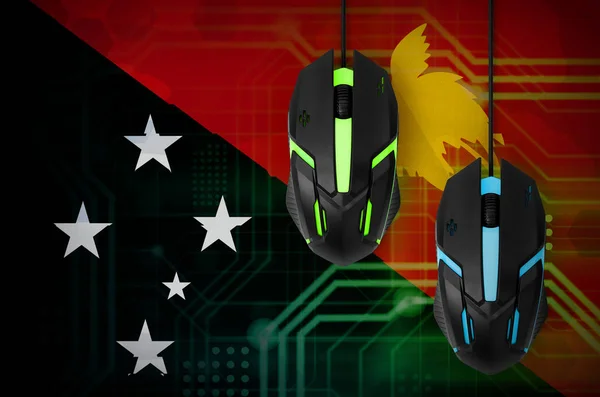 Papua New Guinea flag  and two modern computer mice with backlight. The concept of online cooperative games. Cyber sport team