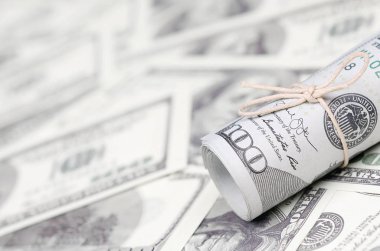 Bize dolar haddelenmiş ve grup ile sıkılaştırılmış bir sürü Amerikan banknotları bulanık arka plan ile yatıyor. Para büyük miktarda