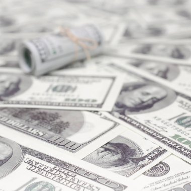 Bize dolar haddelenmiş ve grup ile sıkılaştırılmış bir sürü Amerikan banknotları bulanık arka plan ile yatıyor. Para büyük miktarda