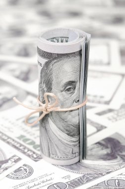 Bize dolar haddelenmiş ve grup ile sıkılaştırılmış bir sürü Amerikan banknotları bulanık arka plan ile yatıyor. Para büyük miktarda