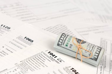 Vergi formları yüz dolarlık faturaları rulo yakın yatıyor. Gelir vergisi iadesi. Vergi kavramı ödeme zamanı. 1040 1041 1120 ve 1065 boş boş formlar