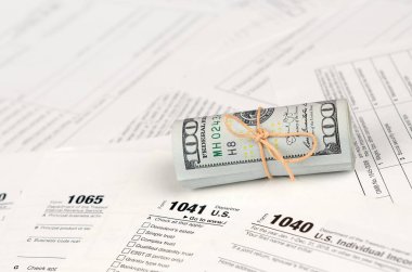 Vergi formları yüz dolarlık faturaları rulo yakın yatıyor. Gelir vergisi iadesi. Vergi kavramı ödeme zamanı. 1040 1041 1120 ve 1065 boş boş formlar