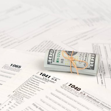 Vergi formları yüz dolarlık faturaları rulo yakın yatıyor. Gelir vergisi iadesi. Vergi kavramı ödeme zamanı. 1040 1041 1120 ve 1065 boş boş formlar