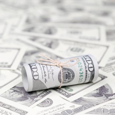 Bize dolar haddelenmiş ve grup ile sıkılaştırılmış bir sürü Amerikan banknotları bulanık arka plan ile yatıyor. Para büyük miktarda