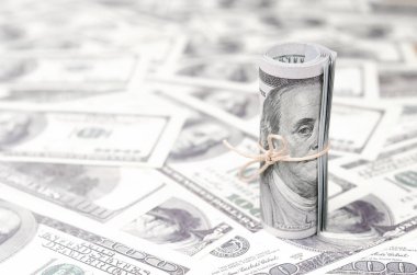 Bize dolar haddelenmiş ve grup ile sıkılaştırılmış bir sürü Amerikan banknotları bulanık arka plan ile yatıyor. Para büyük miktarda