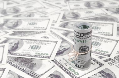 Bize dolar haddelenmiş ve grup ile sıkılaştırılmış bir sürü Amerikan banknotları bulanık arka plan ile yatıyor. Para büyük miktarda