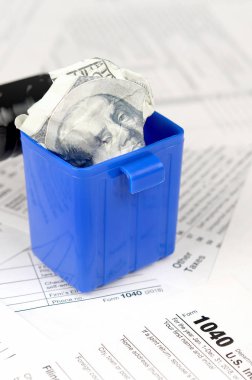 Birçok Amerikan vergisi boş formları ve çöp kutusunda yüz dolarlık banknotu. Vergiler kavramı ödemek için para kaybı