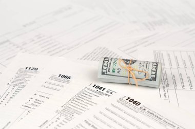 Vergi formları yüz dolarlık faturaları rulo yakın yatıyor. Gelir vergisi iadesi. Vergi kavramı ödeme zamanı. 1040 1041 1120 ve 1065 boş boş formlar