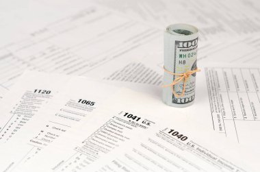 Vergi formları yüz dolarlık faturaları rulo yakın yatıyor. Gelir vergisi iadesi. Vergi kavramı ödeme zamanı. 1040 1041 1120 ve 1065 boş boş formlar