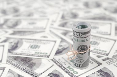 Bize dolar haddelenmiş ve grup ile sıkılaştırılmış bir sürü Amerikan banknotları bulanık arka plan ile yatıyor. Para büyük miktarda