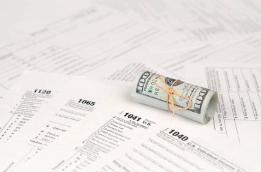 Vergi formları yüz dolarlık faturaları rulo yakın yatıyor. Gelir vergisi iadesi. Vergi kavramı ödeme zamanı. 1040 1041 1120 ve 1065 boş boş formlar