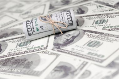 Bize dolar haddelenmiş ve grup ile sıkılaştırılmış bir sürü Amerikan banknotları bulanık arka plan ile yatıyor. Para büyük miktarda