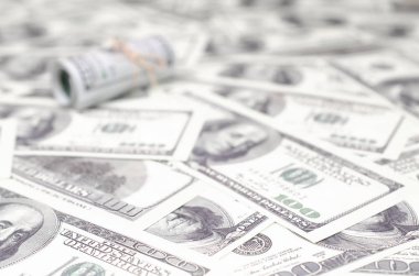 Bize dolar haddelenmiş ve grup ile sıkılaştırılmış bir sürü Amerikan banknotları bulanık arka plan ile yatıyor. Para büyük miktarda