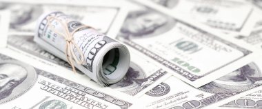 Bize dolar haddelenmiş ve grup ile sıkılaştırılmış bir sürü Amerikan banknotları bulanık arka plan ile yatıyor. Para büyük miktarda