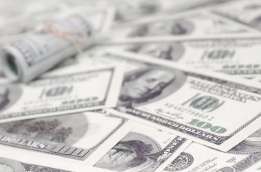 Bize dolar haddelenmiş ve grup ile sıkılaştırılmış bir sürü Amerikan banknotları bulanık arka plan ile yatıyor. Para büyük miktarda