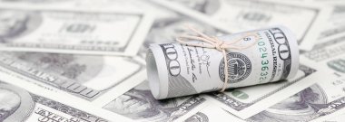 Bize dolar haddelenmiş ve grup ile sıkılaştırılmış bir sürü Amerikan banknotları bulanık arka plan ile yatıyor. Para büyük miktarda