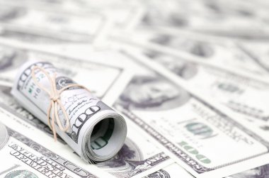 Bize dolar haddelenmiş ve grup ile sıkılaştırılmış bir sürü Amerikan banknotları bulanık arka plan ile yatıyor. Para büyük miktarda