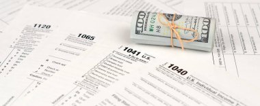 Vergi formları yüz dolarlık faturaları rulo yakın yatıyor. Gelir vergisi iadesi. Vergi kavramı ödeme zamanı. 1040 1041 1120 ve 1065 boş boş formlar