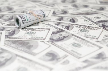 Bize dolar haddelenmiş ve grup ile sıkılaştırılmış bir sürü Amerikan banknotları bulanık arka plan ile yatıyor. Para büyük miktarda
