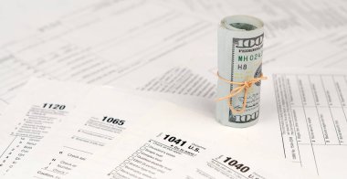 Vergi formları yüz dolarlık faturaları rulo yakın yatıyor. Gelir vergisi iadesi. Vergi kavramı ödeme zamanı. 1040 1041 1120 ve 1065 boş boş formlar