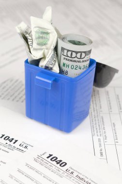 Birçok Amerikan vergisi boş formları ve çöp kutusunda yüz dolarlık banknotu. Vergiler kavramı ödemek için para kaybı