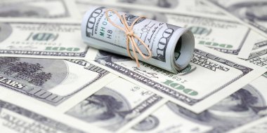 Bize dolar haddelenmiş ve grup ile sıkılaştırılmış bir sürü Amerikan banknotları bulanık arka plan ile yatıyor. Para büyük miktarda