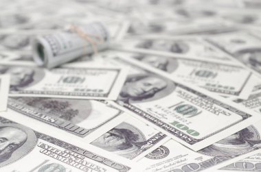 Bize dolar haddelenmiş ve grup ile sıkılaştırılmış bir sürü Amerikan banknotları bulanık arka plan ile yatıyor. Para büyük miktarda