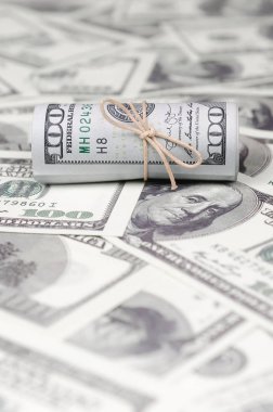 Bize dolar haddelenmiş ve grup ile sıkılaştırılmış bir sürü Amerikan banknotları bulanık arka plan ile yatıyor. Para büyük miktarda