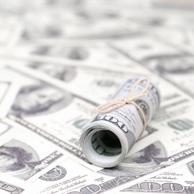 Bize dolar haddelenmiş ve grup ile sıkılaştırılmış bir sürü Amerikan banknotları bulanık arka plan ile yatıyor. Para büyük miktarda