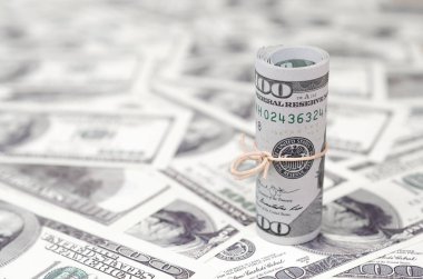 Bize dolar haddelenmiş ve grup ile sıkılaştırılmış bir sürü Amerikan banknotları bulanık arka plan ile yatıyor. Para büyük miktarda