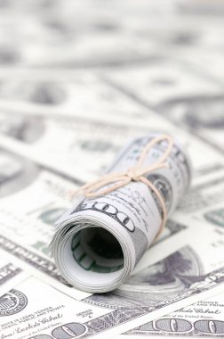 Bize dolar haddelenmiş ve grup ile sıkılaştırılmış bir sürü Amerikan banknotları bulanık arka plan ile yatıyor. Para büyük miktarda