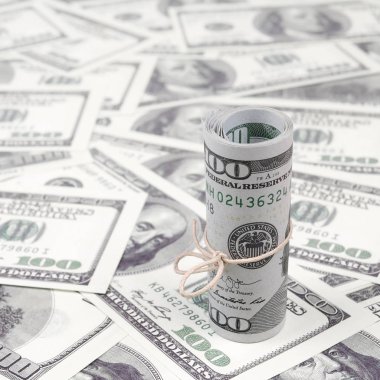 Bize dolar haddelenmiş ve grup ile sıkılaştırılmış bir sürü Amerikan banknotları bulanık arka plan ile yatıyor. Para büyük miktarda