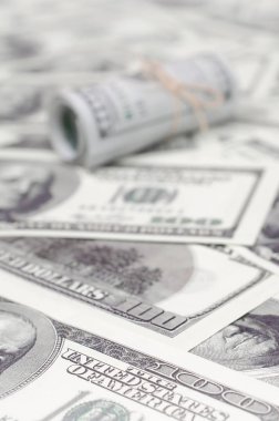 Bize dolar haddelenmiş ve grup ile sıkılaştırılmış bir sürü Amerikan banknotları bulanık arka plan ile yatıyor. Para büyük miktarda