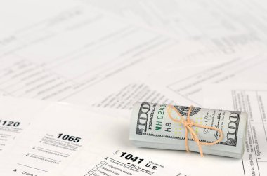 Vergi formları yüz dolarlık faturaları rulo yakın yatıyor. Gelir vergisi iadesi. Vergi kavramı ödeme zamanı. 1040 1041 1120 ve 1065 boş boş formlar
