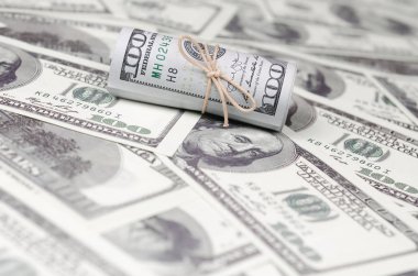 Bize dolar haddelenmiş ve grup ile sıkılaştırılmış bir sürü Amerikan banknotları bulanık arka plan ile yatıyor. Para büyük miktarda