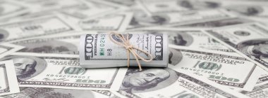Bize dolar haddelenmiş ve grup ile sıkılaştırılmış bir sürü Amerikan banknotları bulanık arka plan ile yatıyor. Para büyük miktarda