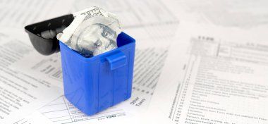 Birçok Amerikan vergisi boş formları ve çöp kutusunda yüz dolarlık banknotu. Vergiler kavramı ödemek için para kaybı