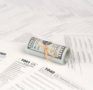 Vergi formları yüz dolarlık faturaları rulo yakın yatıyor. Gelir vergisi iadesi. Vergi kavramı ödeme zamanı. 1040 1041 1120 ve 1065 boş boş formlar