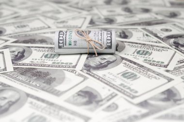 Bize dolar haddelenmiş ve grup ile sıkılaştırılmış bir sürü Amerikan banknotları bulanık arka plan ile yatıyor. Para büyük miktarda