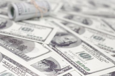 Bize dolar haddelenmiş ve grup ile sıkılaştırılmış bir sürü Amerikan banknotları bulanık arka plan ile yatıyor. Para büyük miktarda