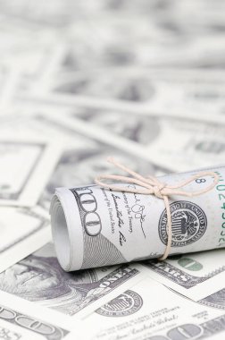Bize dolar haddelenmiş ve grup ile sıkılaştırılmış bir sürü Amerikan banknotları bulanık arka plan ile yatıyor. Para büyük miktarda
