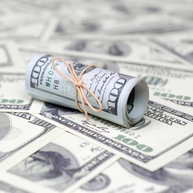 Bize dolar haddelenmiş ve grup ile sıkılaştırılmış bir sürü Amerikan banknotları bulanık arka plan ile yatıyor. Para büyük miktarda