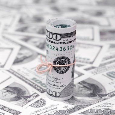Bize dolar haddelenmiş ve grup ile sıkılaştırılmış bir sürü Amerikan banknotları bulanık arka plan ile yatıyor. Para büyük miktarda